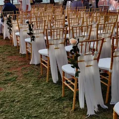 For this outdoor ceremony, we decorated the guest chairs with flowing white drapes and a single, elegant rose. This simple touch adds a layer of sophistication to the seating arrangement.