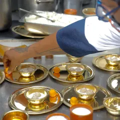 We take great care in plating our dishes, even for large orders. Here, we are preparing individual thalis, ensuring each bowl of Pidi Kozhukatta is perfectly presented before it goes out.