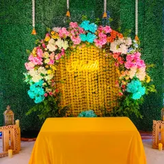 For a modern twist on Haldi decor, I created this backdrop using a green grass wall, a curtain of marigolds, and a vibrant multi-colored floral arch.