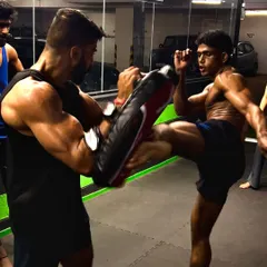 A perfect display of power and technique. One of our fighters executes a powerful kick during a pad work session, demonstrating the precision and force we cultivate in our striking classes.