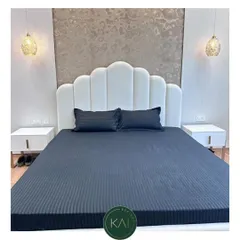 A close-up of the white scalloped headboard, showing the detail of the vertical tufting. This design adds a touch of softness and sophistication to the bedroom, creating a comfortable and stylish backdrop.