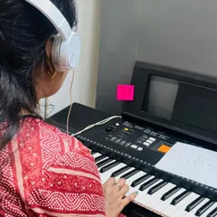 A student practices her piece on the keyboard, using headphones for focused learning. This setup is common in our group classes, allowing each student to practice at their own pace.