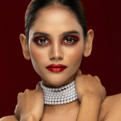 A bold beauty portrait with dramatic red eyeshadow and lipstick, paired with a classic pearl choker for a striking contrast.