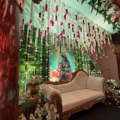 Another angle of the Krishna-themed baby shower decor, showing the depth created by the layered floral hangings and the soft green lighting.