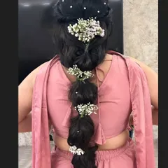A messy bubble braid decorated with baby's breath and pearls. This is a fun and modern hairstyle, perfect for a bridesmaid or for a sangeet.