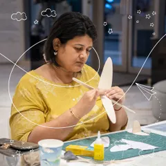 The first step in aviation is understanding the form. Here, a participant carefully assembles the wings of her glider, learning how each component contributes to stable flight. It's a hands-on lesson in aerodynamics and craftsmanship.