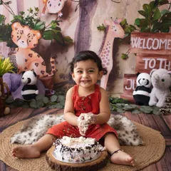 The best part of a cake smash. This happy one-year-old is enjoying his cake in a fun jungle-themed setup.