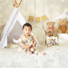 A classic portrait from a first-year milestone session. This baby is sitting up in a cozy tent-themed set, looking curiously at the camera.