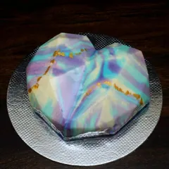 A heart-shaped mousse cake with a stunning mirror glaze finish. I created a marbled effect using pastel shades of purple, blue, and yellow, with touches of gold leaf for a truly artistic look.