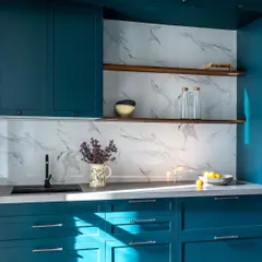 This kitchen from the Bombay Blue home is bold and embraces color. The deep teal cabinets and custom stained-glass arched door make a beautiful statement, nodding to old Bombay's Art Deco style.