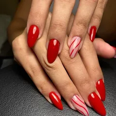 A bold red manicure with two accent nails featuring candy cane-like stripes for a festive touch.