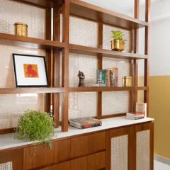 A detail shot of the custom foyer shelving unit, showcasing the craftsmanship of the teak and cane work. The white marble top adds a clean, contrasting surface for display.