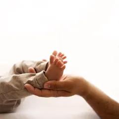 Tiny feet held securely in dad's hand. This shot emphasizes just how small and precious they are in these first few weeks. A classic newborn detail shot.