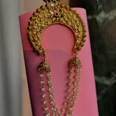 A close-up of the crescent-shaped khopa, showing the intricate design and the small jhumkas at the top.