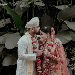 A tender moment between the bride and groom amidst lush greenery. This portrait, taken right after the main rituals, shows the quiet happiness of finally being married.