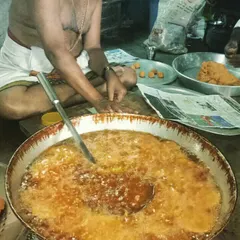 This is how we prepare our fried snacks for large orders and catering events. One of our senior cooks is frying a batch of sweets in a large kadai, ensuring every piece is cooked evenly and traditionally.