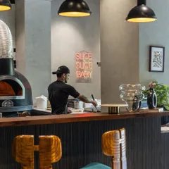 Here’s a glimpse of where the magic happens. My open kitchen, with the wood-fired oven at its heart and our pizzaiolo at work, is central to the chill, modern trattoria vibe. It’s a place to linger, watch the action, and feel like part of the family.
