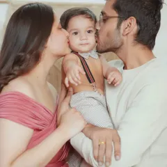 Kisses for the little one! This is a classic family portrait pose that beautifully captures the love and adoration parents have for their child.