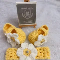 A sunny and bright accessory set, this includes yellow booties and a matching headband, both adorned with a white flower that has a sparkling center.