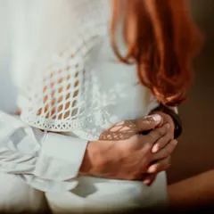 A close-up shot of hands intertwined, with beautiful dappled light creating patterns on the skin. This artistic detail from a Delhi shoot highlights the simple, profound connection of touch.