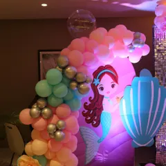 A closer look at the details of our mermaid theme decor. The custom-printed mermaid character and seashell cutouts are paired with a pastel balloon garland to complete the underwater look.