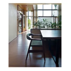 Simplicity and natural materials define the dining space. The clean lines of the wooden furniture and flooring are complemented by the natural light and greenery, creating a calm and inviting atmosphere for family gatherings.