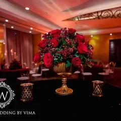 A luxurious centerpiece featuring a bouquet of deep red roses in a golden vase. This classic and elegant detail was part of a glamorous red-themed reception.