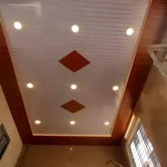 A simple and elegant PVC ceiling with a wood-panelled border. The main ceiling is white with integrated spotlights, and the diamond-shaped wood inlays add a touch of custom detail.