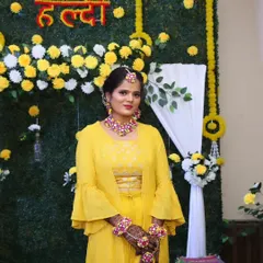 A full-length view of a bride on her Haldi day, dressed in a vibrant yellow outfit and adorned with floral jewelry.