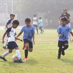 Two young opponents battle for possession in a School Soccer League match. These moments of healthy competition are where skills are tested and sportsmanship is learned on the field.