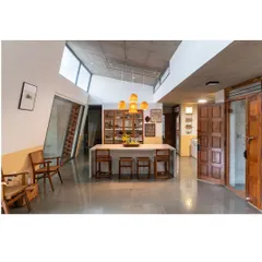 The heart of the Aamra house, where the kitchen and dining areas converge. This open-plan space is designed for gathering, featuring a polished concrete island, upcycled wood cabinetry, and an exposed concrete ceiling, reflecting our principle of material honesty.