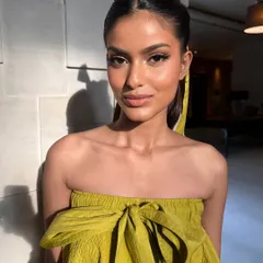 A direct shot of the sunkissed editorial look. The makeup is minimal yet impactful, focusing on a flawless complexion and a precise cat-eye to make the eyes pop.