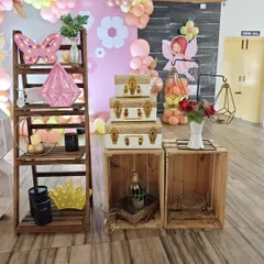 A collection of rustic and chic props, including a wooden ladder shelf, decorative suitcases, and geometric lanterns, used to style a fairy-themed party.