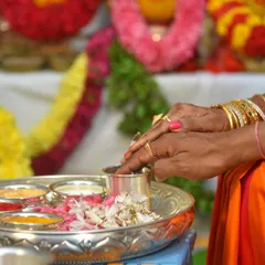 A close-up of hands performing a ritual during a housewarming pooja. This type of detail shot captures the action and significance of the ceremony.