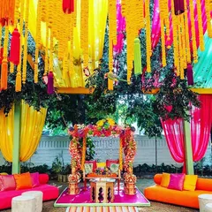 Let's bring the fun to your pre-wedding festivities. This vibrant Mehendi or Sangeet setup is bursting with color, featuring bright fabric drapes, traditional marigold hangings, and comfortable, stylish seating for a day of celebration.