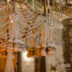 The exquisite craftsmanship of our pearl and floral chandelier. This close-up shows the hand-strung pearls, delicate fabric flowers, and small golden baubles that make this piece so special.
