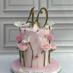A sophisticated cake for a 40th birthday. The soft pink tier is decorated with delicate, individually placed sugar flowers and butterflies, creating the look of a whimsical garden growing up the side of the cake.