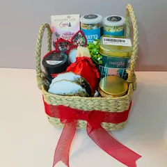 This Kauna basket is filled with a mix of savory snacks, sweets, and festive decor, all tied with a bright red ribbon for a celebratory touch.