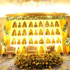 A wider view of the Haldi stage, showcasing the plush seating for the couple, framed by a bed of fresh sunflowers and a beautifully illuminated backdrop.