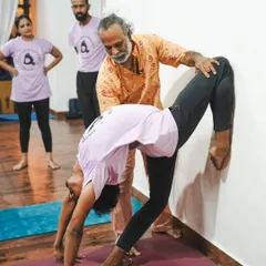 With hands-on guidance, I help a student find more depth and openness in a wall-supported backbend. This personalized attention is a core part of my teaching philosophy.