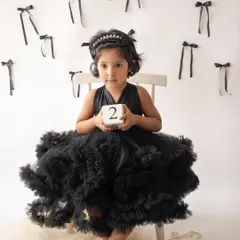 Celebrating turning two with a stylish photoshoot. This little girl is wearing a beautiful black tulle dress, holding a number block to mark her milestone.