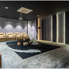 The design incorporates textured wall panels and vertical light strips to create a dramatic, immersive atmosphere. The dark color palette minimizes light reflection, enhancing the on-screen picture quality.
