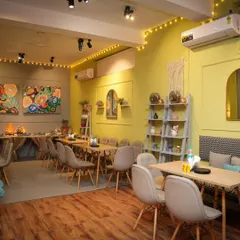 I welcome you all to a cozy space where you can make memories together. This is our cafe area, set up for a private event with warm lighting and comfortable seating.