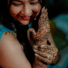 A close up shot capturing the bride's smile as she admires the intricate patterns of her bridal mehndi.
