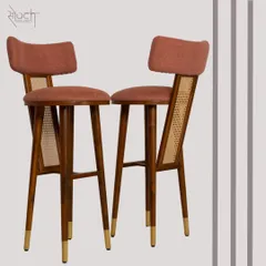 The 'Lithe Perch' high chair, designed for a breakfast or bar space. This custom piece features a teakwood frame, rattan detailing, and brass-capped legs for a look that is both sleek and elegant.