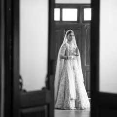 A beautiful black and white portrait of a bride standing in a doorway, the natural light creating a soft and elegant look.