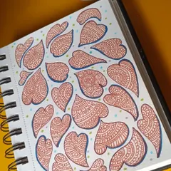 When the days feel hard, I meditate through art. This sketchbook page is filled with heart-shaped doodles, each one filled with intricate zentangle patterns. It's a simple pen drawing exercise for calming anxiety.