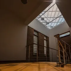 Sunlight bursts through a large skylight, casting strong shadows and illuminating the warm tones of the floor. We design these moments to create a powerful connection with the time of day and the weather outside.