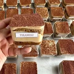 Handling bulk orders is one of my specialties. Here you can see a large order of my authentic Tiramisu tubs, each one consistently prepared and labeled for a corporate client's dessert table setup.