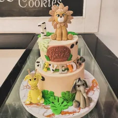 A two-tiered jungle animal cake for a first birthday. This cake is decorated with adorable fondant figures of a lion, giraffe, and elephant, perfect for a safari-themed party.